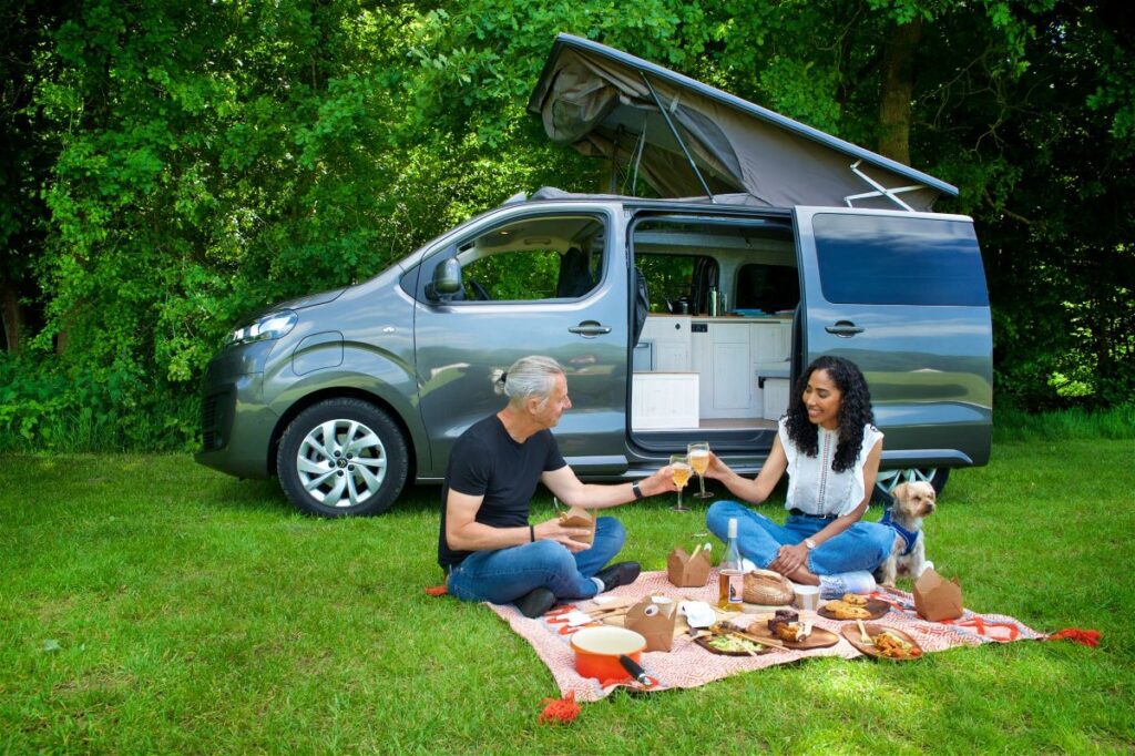 Two people enjoying a picnic next to a campervan